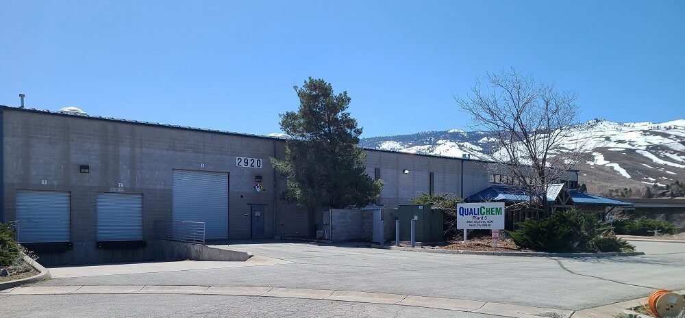 An exterior view of the plant 3 QualiChem building with a mountainous background, showcasing the facility's entrance and signage.