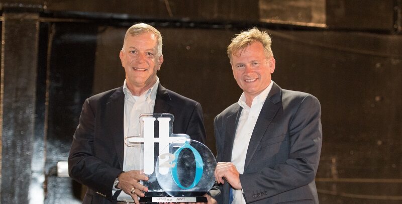 two men smiling holding an award